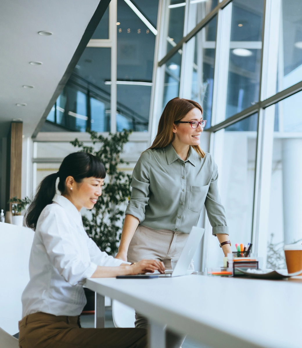 Moderne Glasfassade mit Büros, umgeben von Bäumen, sonniger Tag Moderne Glasfassade mit Büros, umgeben von Bäumen, sonniger Tag