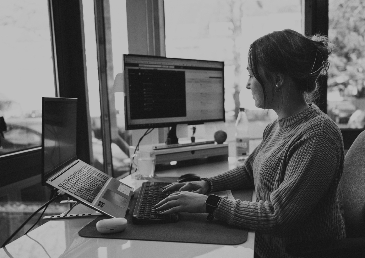 Junge Frau sitzt in einem Schreibtisch im modernen Büro und arbeitet konzentriert