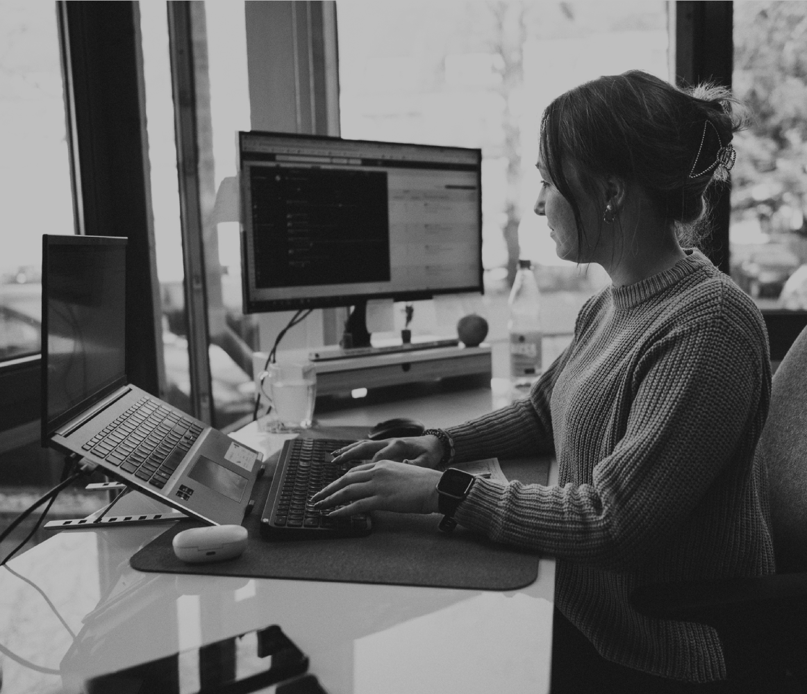 Junge Frau sitzt in einem Schreibtisch im modernen Büro und arbeitet konzentriert