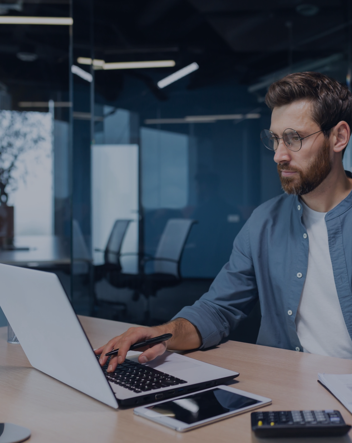 Mann arbeitet konzentriert an einem Laptop in einem modernen Büro. 
