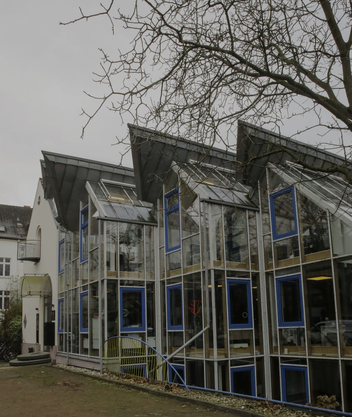 Außenansicht eines Bürogebäudes mit moderner Glasfassade und blauen Fensterrahmen.