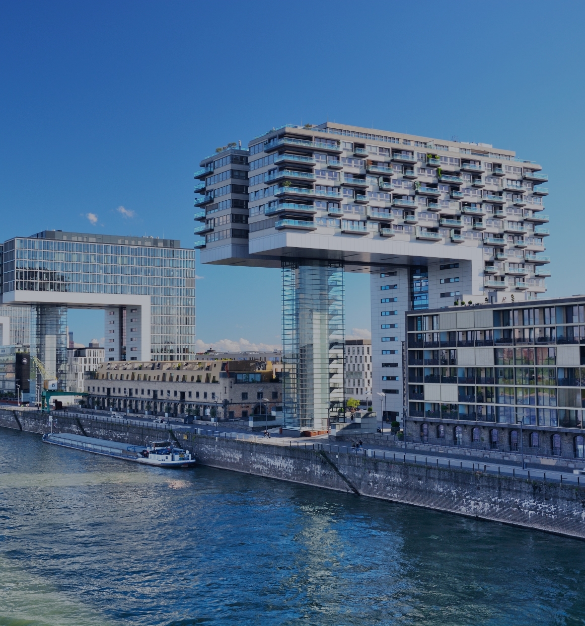 Moderne Kranhäuser am Rhein in Köln mit Blick auf das Rheinufer und ein vorbeifahrendes Schiff
