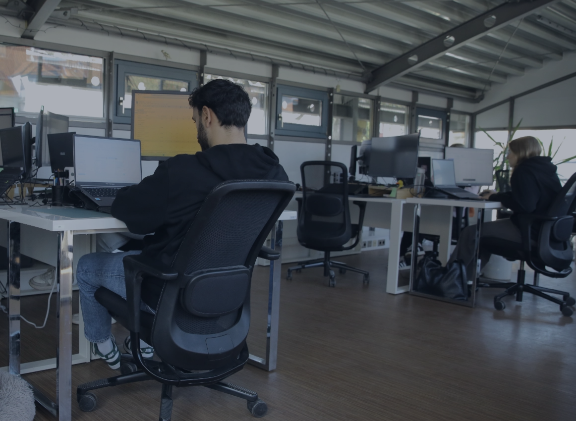 Mehrere Personen arbeiten an Schreibtischen mit Computern in einem modernen Büro