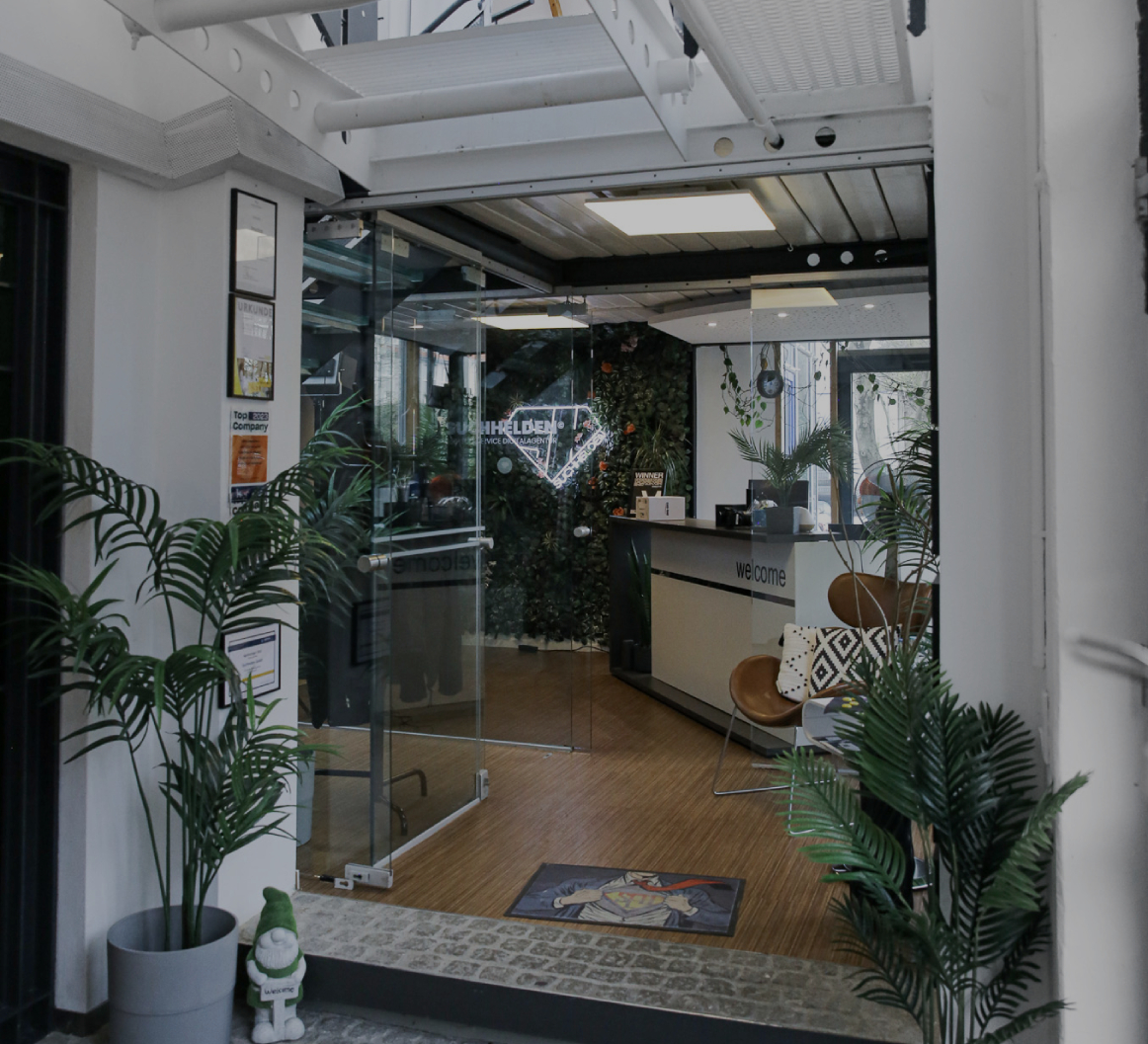 Eingangsbereich eines modernen Bürogebäudes mit Glas_tür, Empfangstresen, Pflanzen und offener Treppenkonstruktion