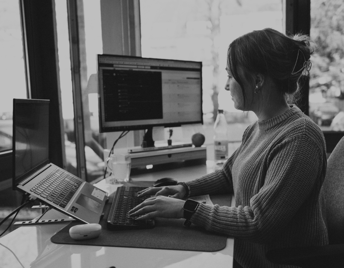 Junge Frau sitzt in einem Schreibtisch im modernen Büro und arbeitet konzentriert