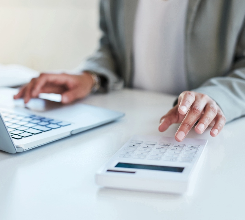 Nahaufnahme einer nicht erkennbaren Geschäftsfrau mit Taschenrechner und Laptop in einem Büro
