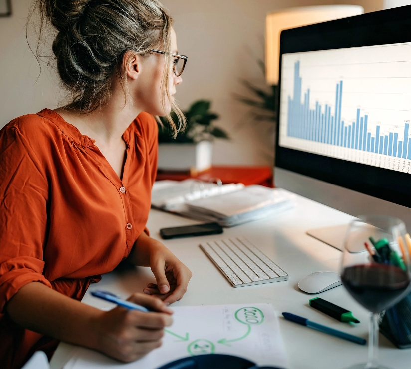 junge Frau sitz vor einem Computer und sieht sich ein Balkendiagramm an 