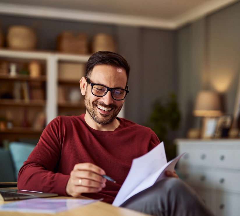 Ein fröhlicher Buchhalter mit Brille, der Finanzberichte liest, während er von zu Hause aus arbeitet