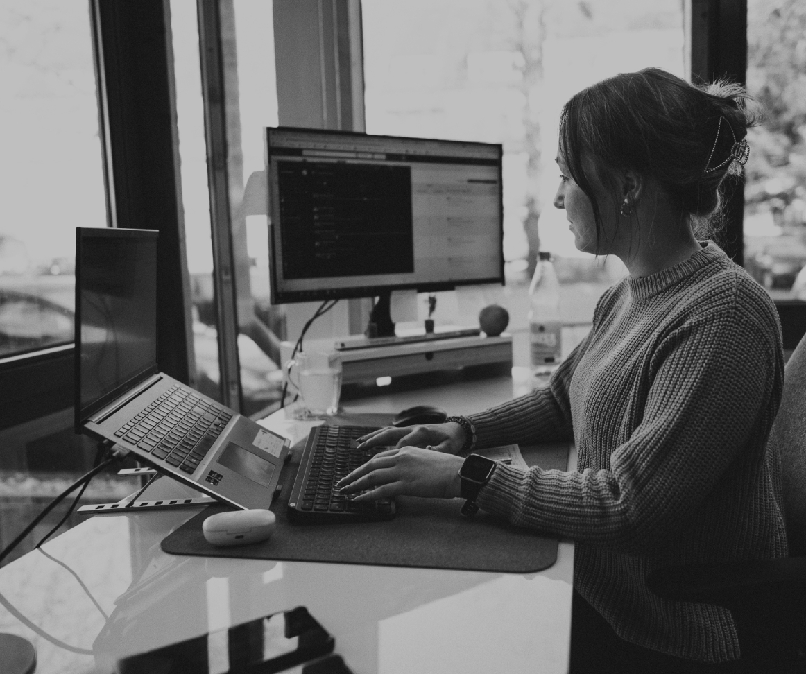 Junge Frau sitzt in einem Schreibtisch im modernen Büro und arbeitet konzentriert